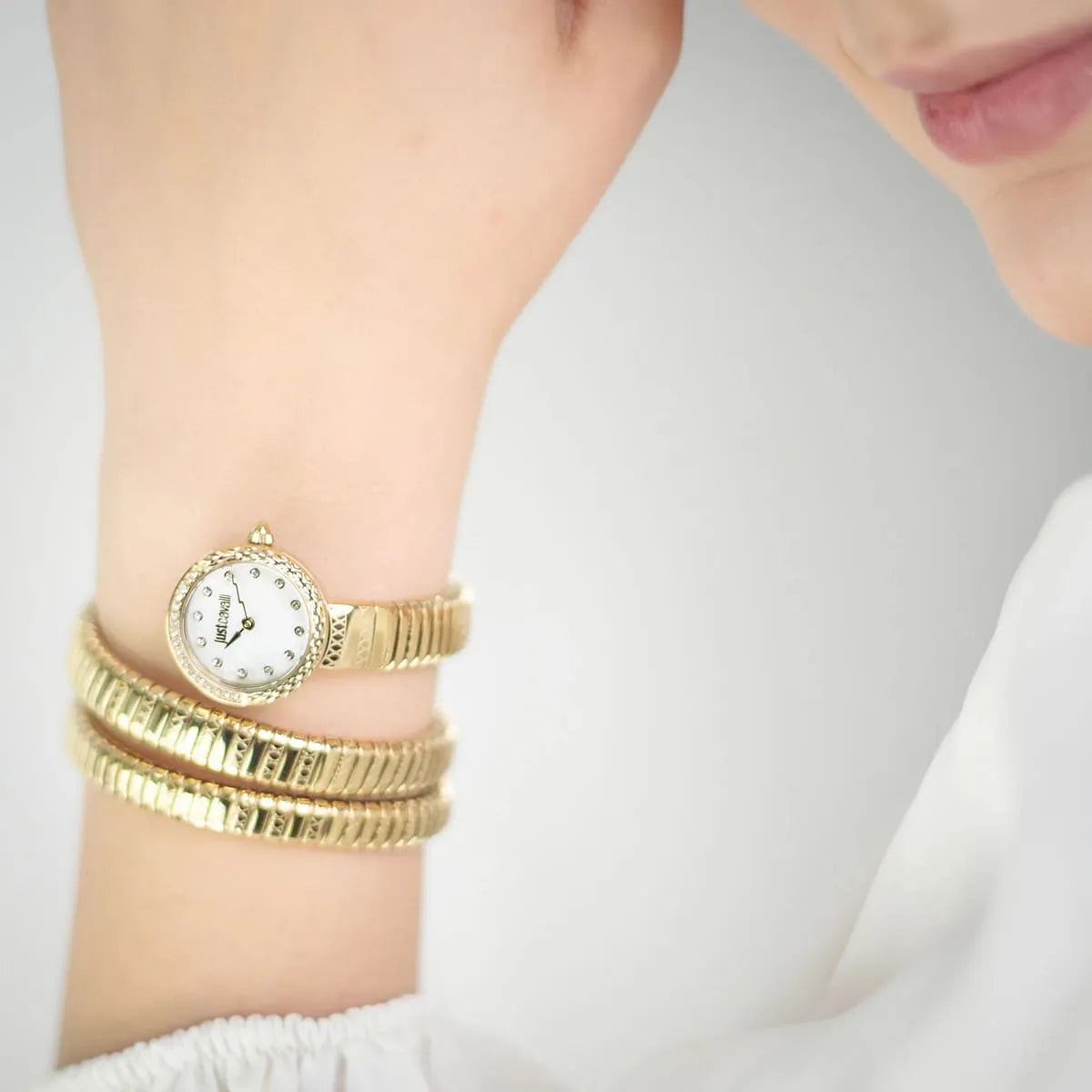 Just Cavalli Signature Snake yellow gold watch with crystal bezel worn on wrist, lifestyle view