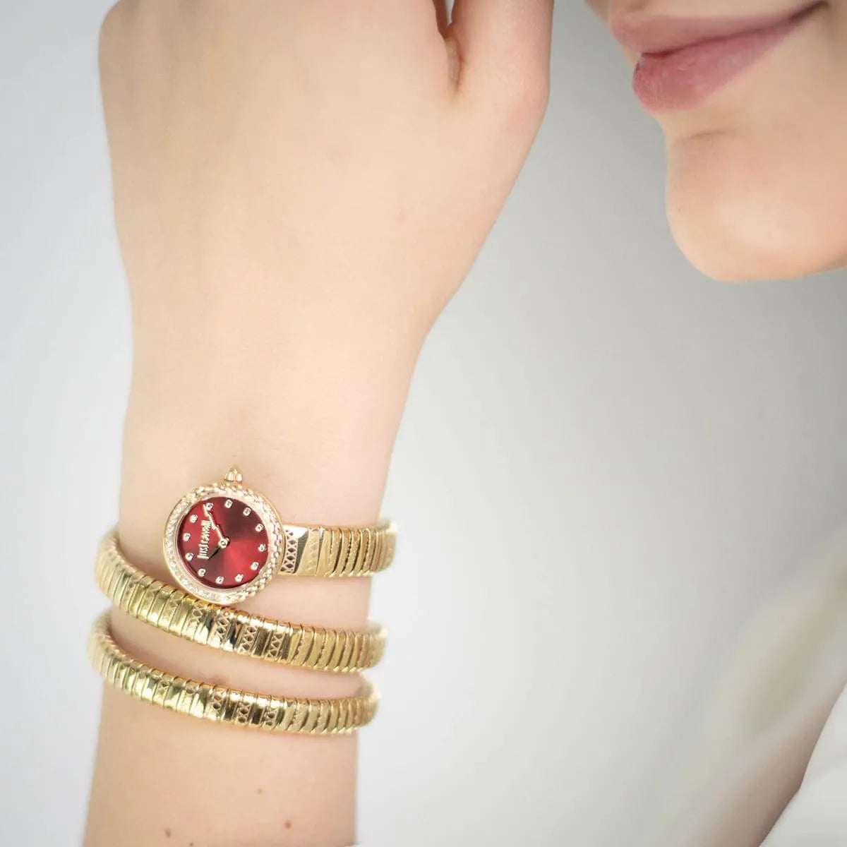 Just Cavalli Enchanting Snake women's watch worn on wrist showing red dial and stacked gold snake straps