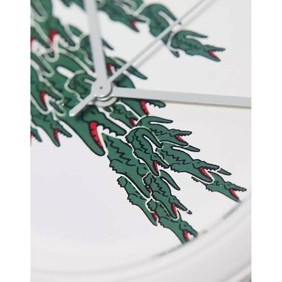 Close-up detail of Lacoste crocodile logo dial showing green crocodile with red accents