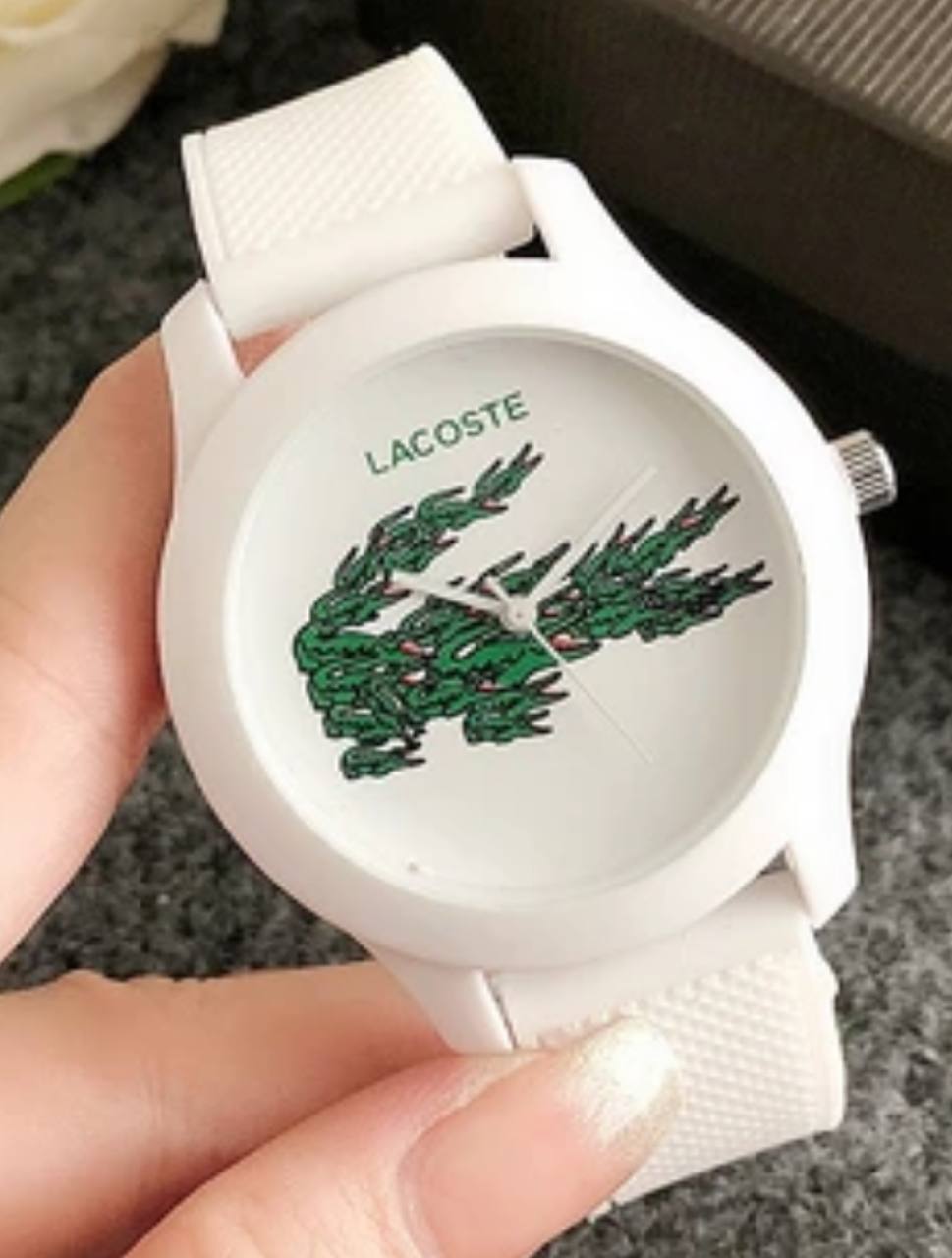 Lacoste watch on wrist showing white case with green crocodile logo and white silicone band