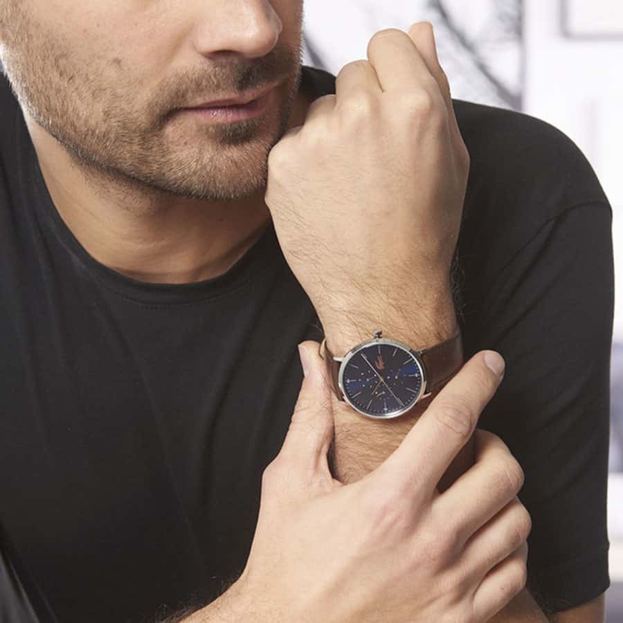 Lacoste Moon Ultra Slim watch worn on man's wrist showing navy dial with rose gold hands and chronograph subdials