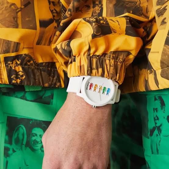 White Lacoste Polaroid watch worn on wrist with colorful crocodile design visible on dial