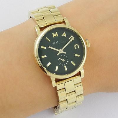 Baker mini women's watch on wrist showing green dial with gold-tone bracelet