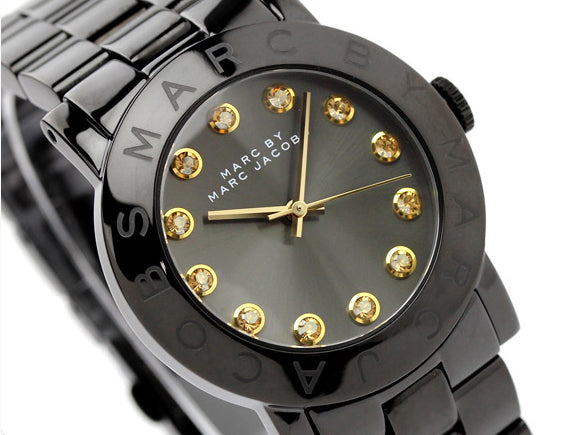 Marc By Marc Jacobs Blade dial detail with gold hour markers and Marc Jacobs branding on black background