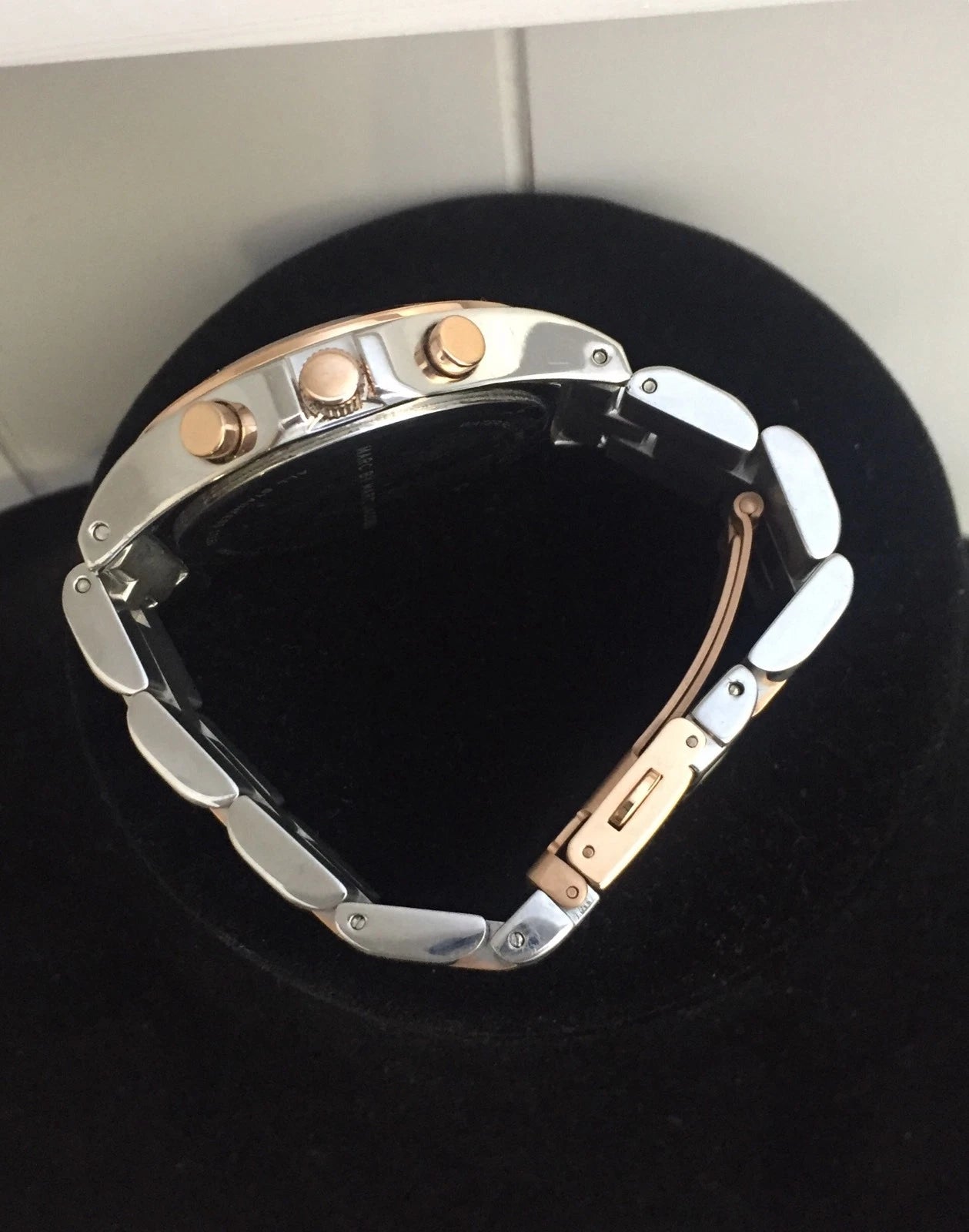 Two-tone stainless steel and rose gold bracelet of MBM3178 on black display stand