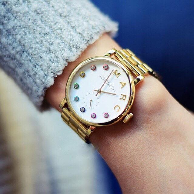 Marc Jacobs Baker gold watch worn on wrist with white dial and colorful markers visible