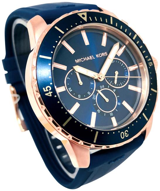 Angled view of Michael Kors Cunningham watch showing blue dial, rose gold case, and blue silicone strap