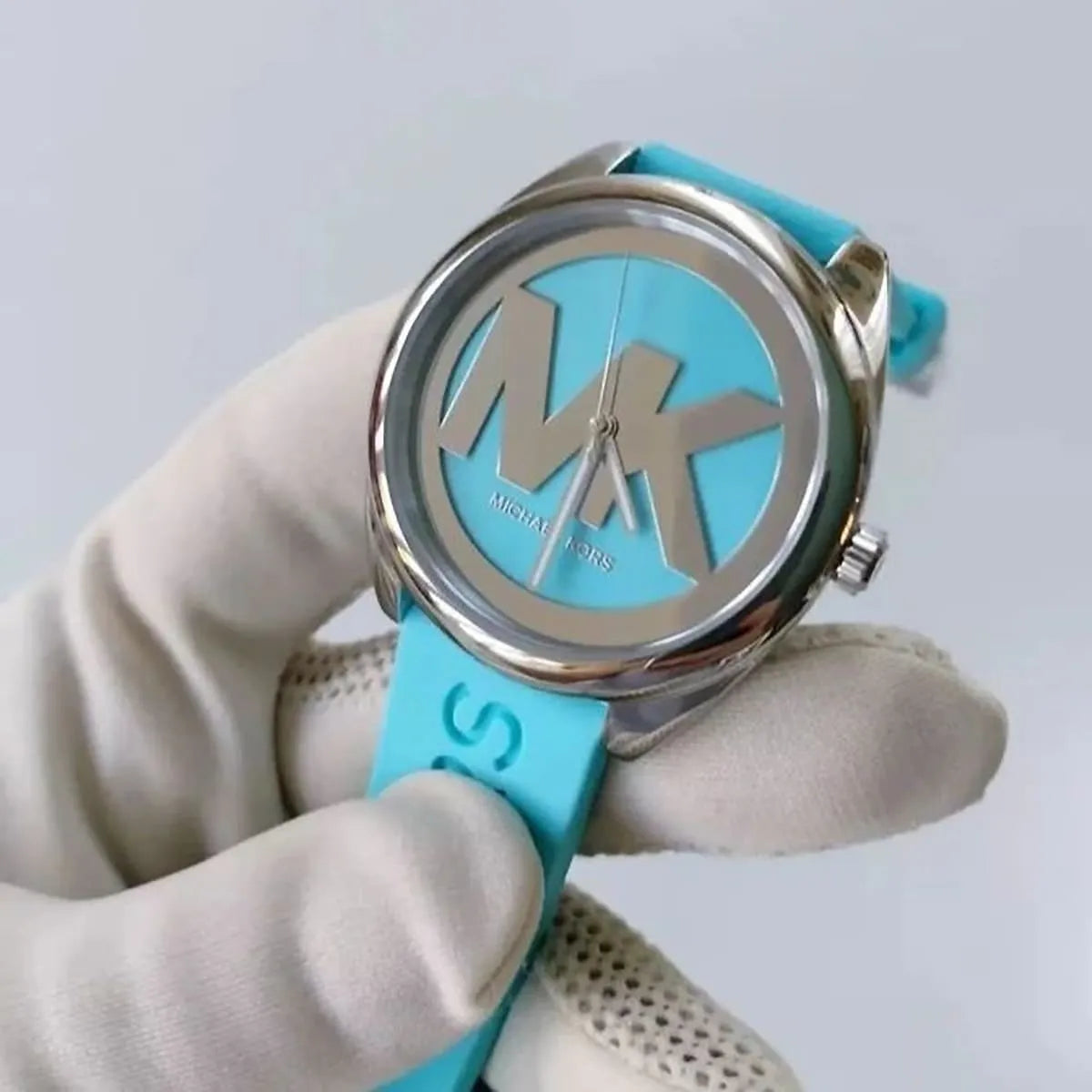 Michael Kors Janelle MK7350 watch in hand showing silver case and turquoise rubber strap