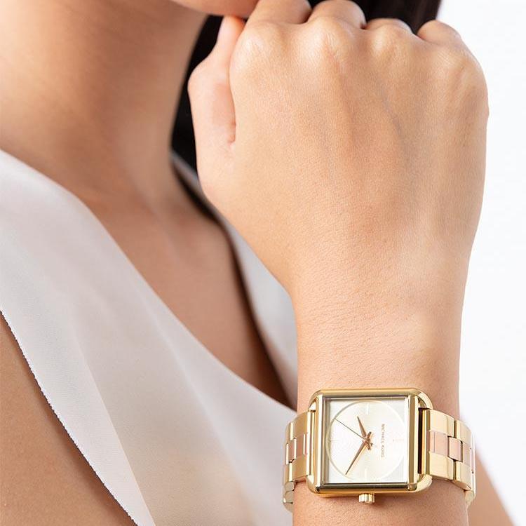 Michael Kors Lake women's watch worn on wrist, showing two-tone bracelet and square case with gold dial