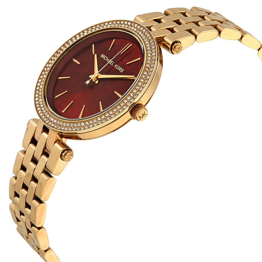 Michael Kors Mini Darci watch at angle showing gold bracelet and garnet dial with diamond bezel