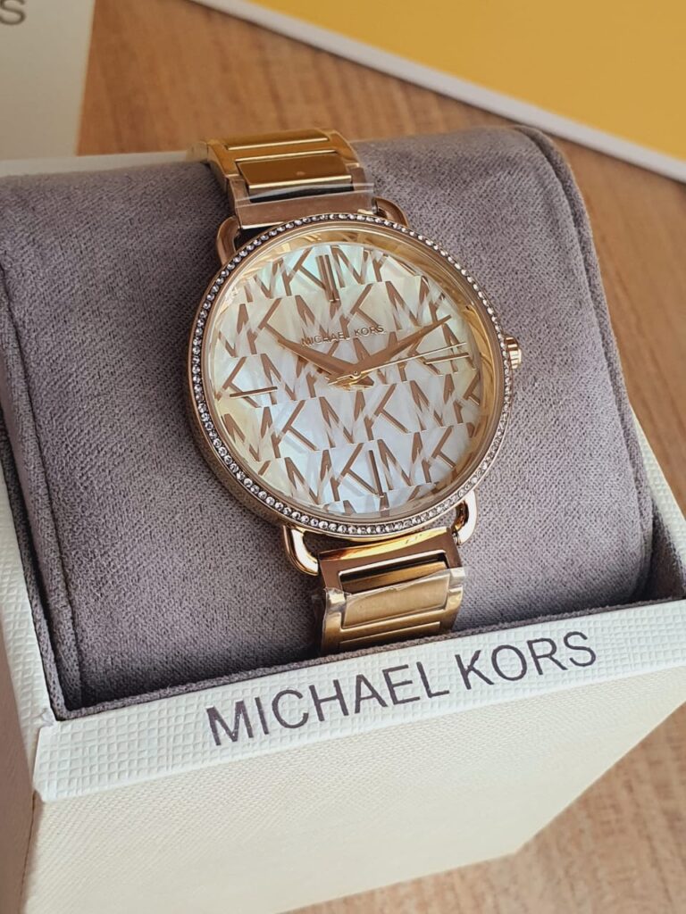 Michael Kors Portia gold tone watch on wrist with gray presentation box
