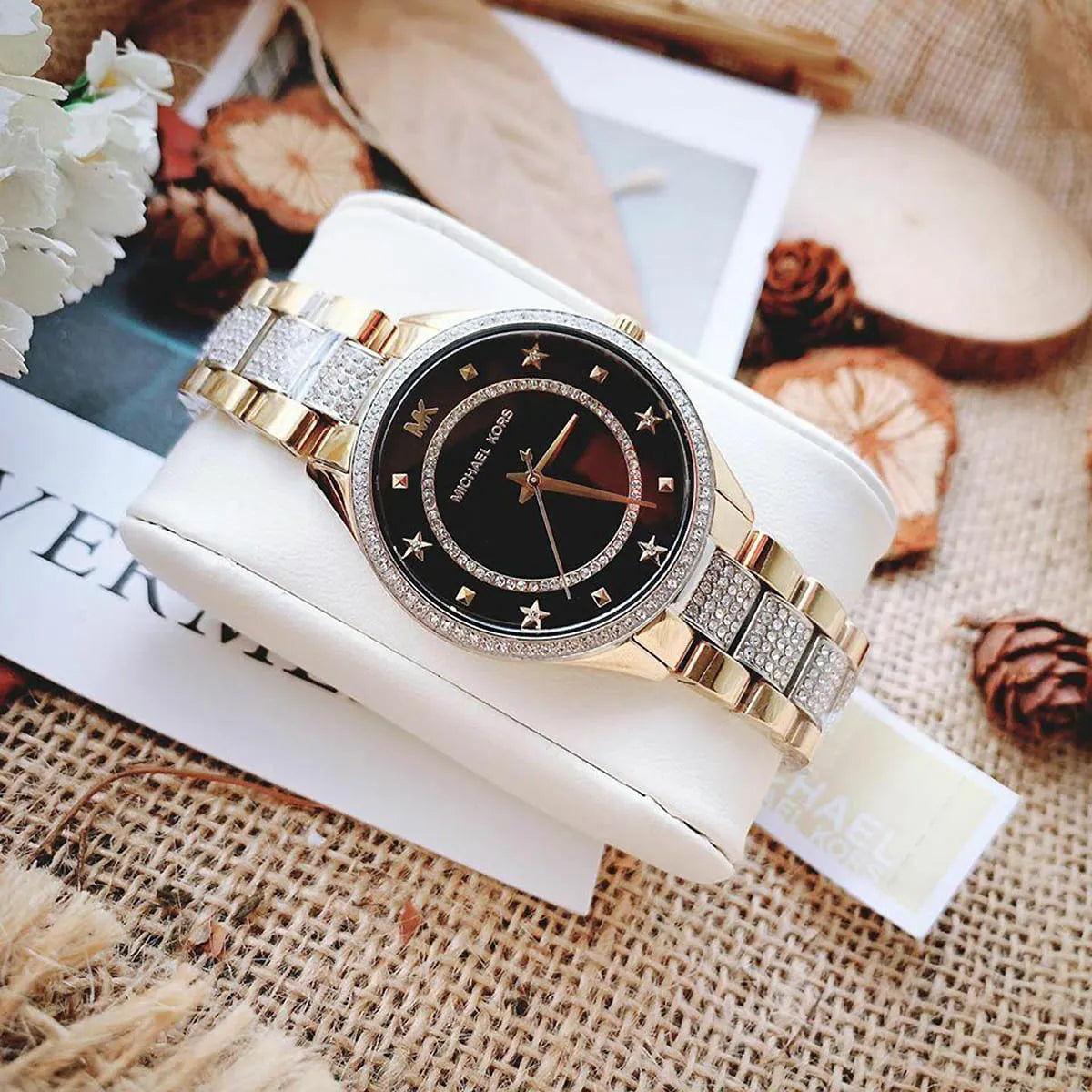 Michael Kors Lauryn watch styled with magazines and flowers showing two-tone strap detail
