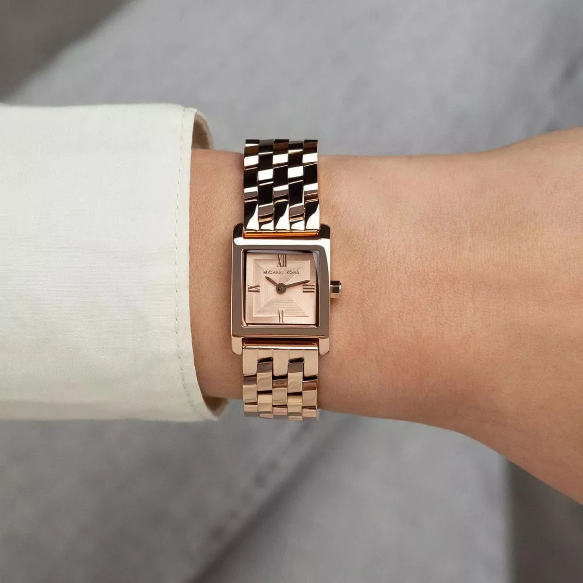 Michael Kors Georgie rose gold watch worn on wrist with white cuff