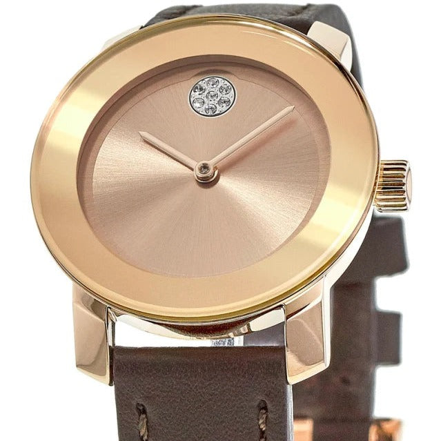 Movado Bold rose gold watch showing rose dial with signature blue sapphire dot and brown strap