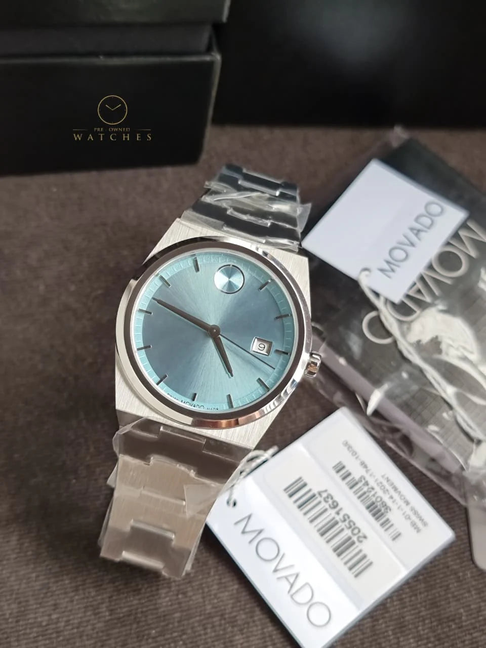Movado BOLD Quest watch displayed with original packaging, warranty cards, and presentation box