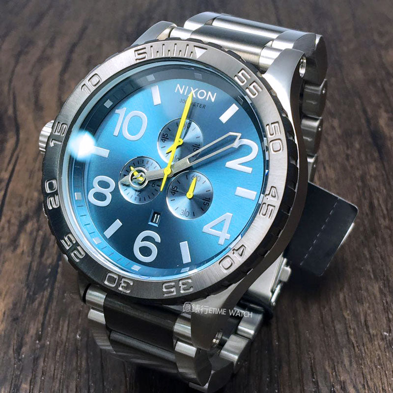 Nixon 51-30 Chronograph angled view showing silver and black stainless steel design with blue dial