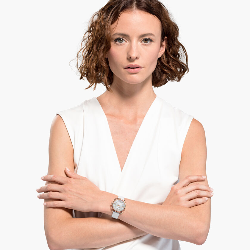 Woman wearing Crystalline Glam rose gold watch with white strap and crystal-adorned white dial