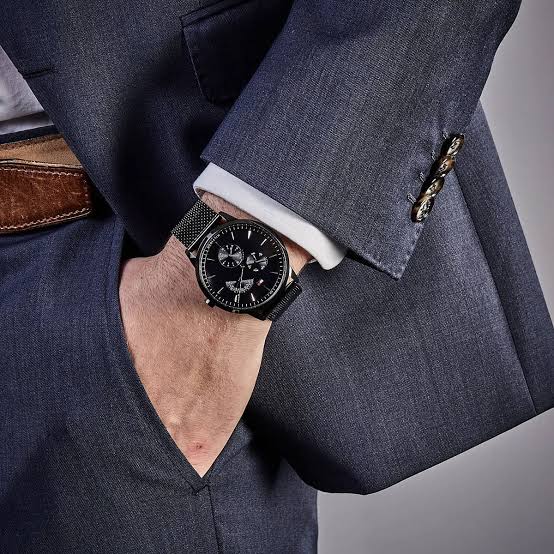 Tommy Hilfiger black dial watch worn on wrist with dark suit