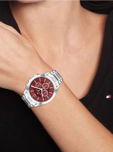 Tommy Hilfiger women's watch with burgundy dial worn on wrist with stainless steel strap