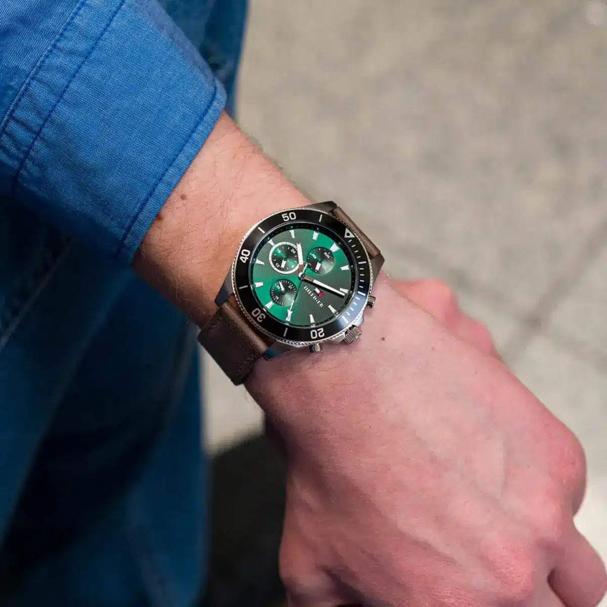 Tommy Hilfiger chronograph watch worn on wrist with green dial and brown strap