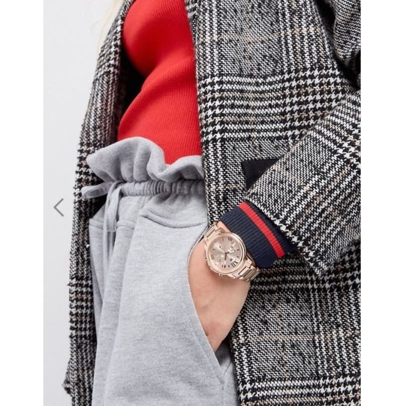 Tommy Hilfiger Claudia rose gold watch worn on wrist with checkered jacket and red sleeve