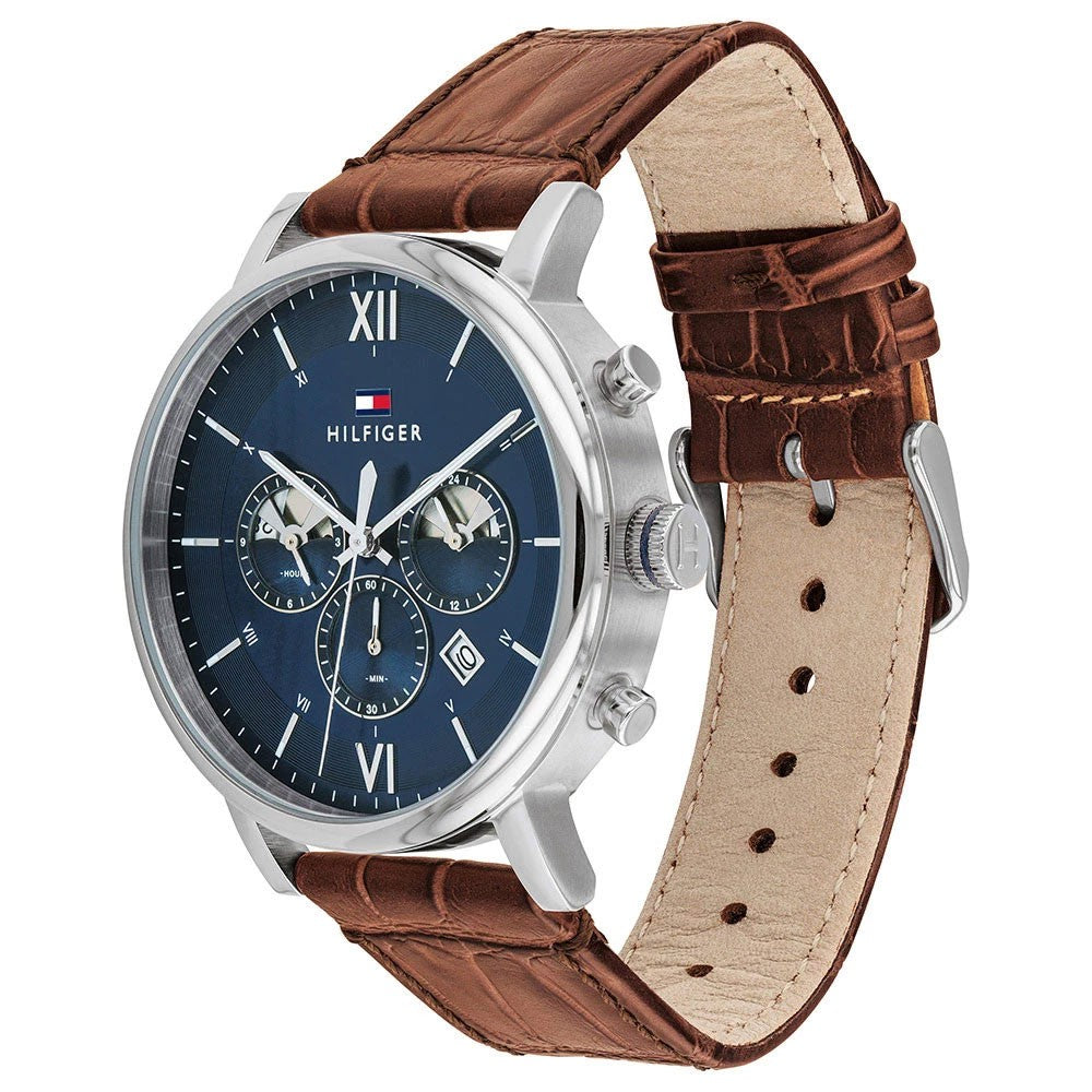 Angled view of Tommy Hilfiger Evan watch showing silver case, navy dial, and brown crocodile leather strap