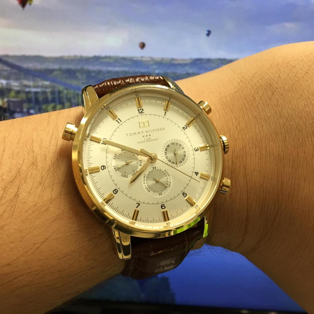 Tommy Hilfiger GMT gold-plated chronograph watch worn on wrist with brown leather strap