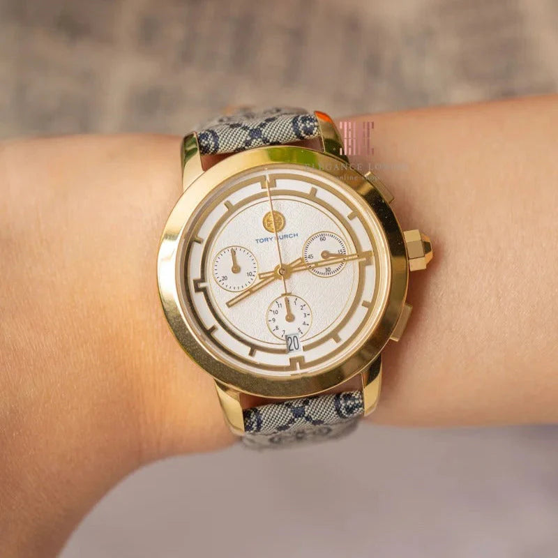 Tory Burch TBW1035 chronograph watch on wrist showing gold case and blue fabric monogram strap