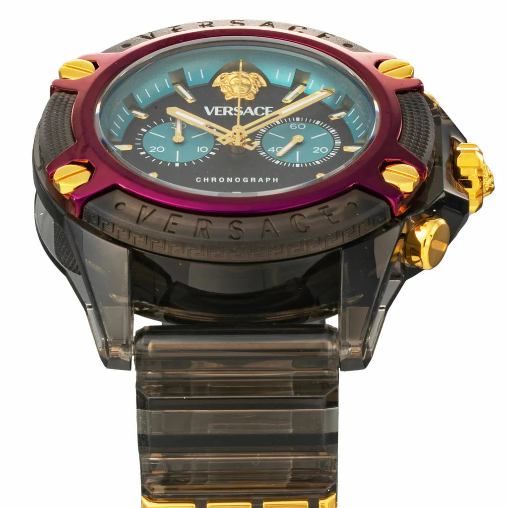 Close-up of chronograph dial with black face, turquoise subdials, gold hands and magenta bezel with gold hour markers