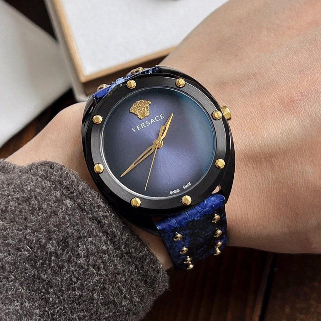 Versace Shadov watch worn on wrist with blue patterned leather strap and gold accents