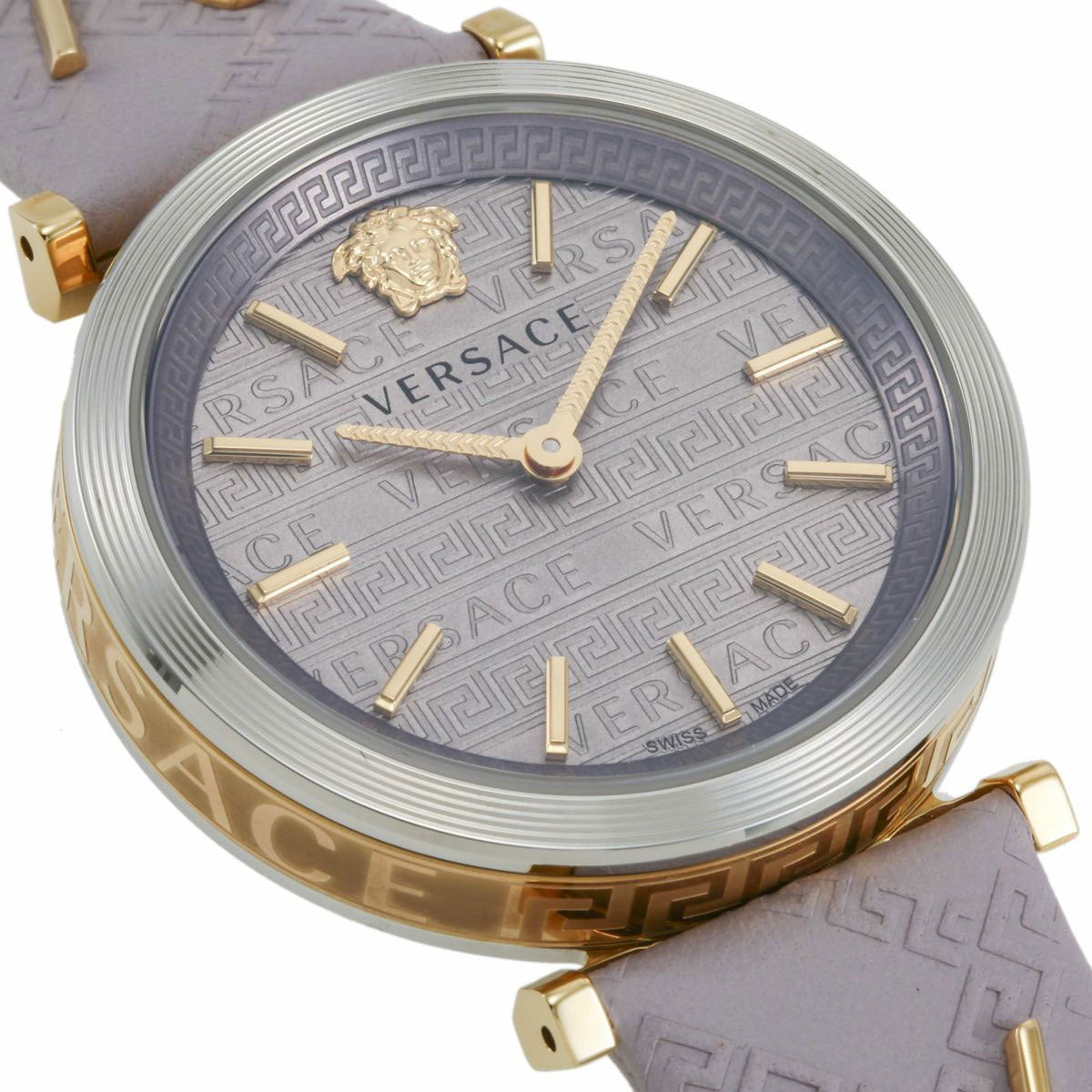 Versace V-Twist watch close-up showing light pink dial with gold-tone Roman numerals and Medusa logo
