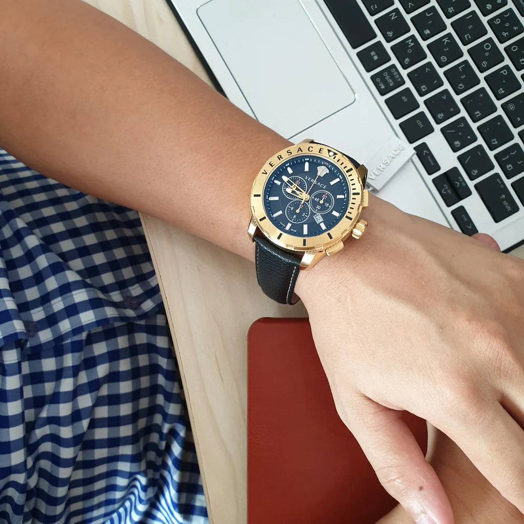 Versace chronograph watch worn on wrist with blue leather strap and gold case