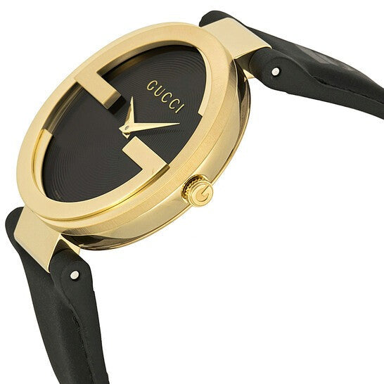 Gucci Grammy watch angled view showing gold case, black dial with Interlocking G, and black leather strap